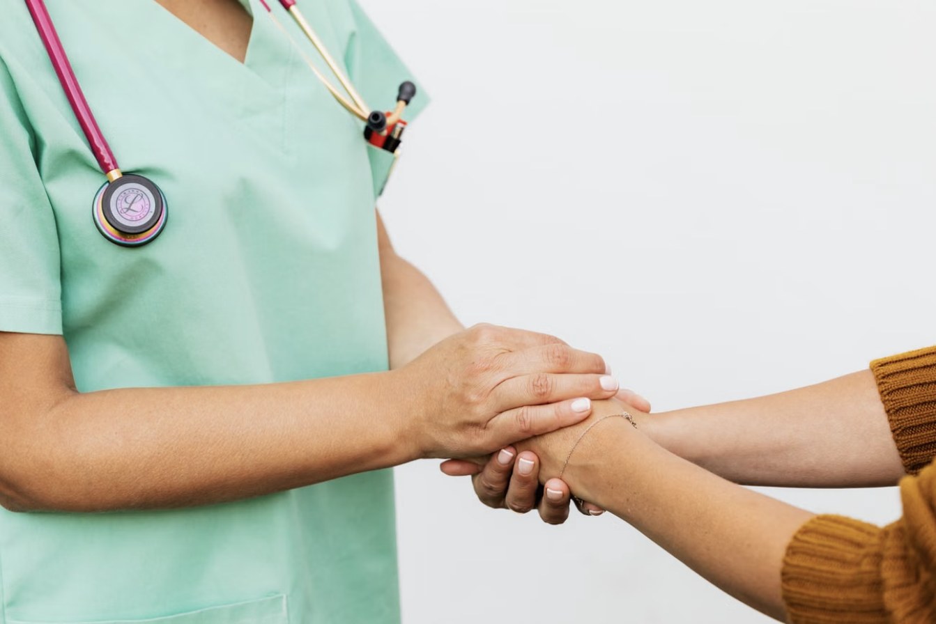 Une soignante tient les mains d’une patiente
